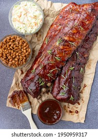 Overhead Image Of An All American Meal Of BBQ Smoked Pork Ribs With Baked Beans, Cole Slaw And Sauce 