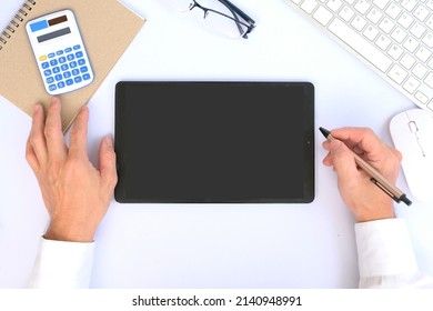 Overhead Image Of A Blank-screen Tablet In A Dark Modern Office Setting With A Laptop Computer And Other Office Supplies.