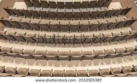 Overhead image of empty tan - gray theater, auditorium seats, chairs.	