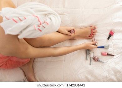 overhead image of woman with towel doing pedicure on bed - Powered by Shutterstock