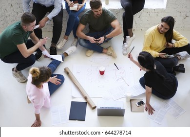 Overhead image of working process of young male and female coworkers choosing successful strategy while drafting together, crew of architects brainstorming in blueprint creation on informal meeting