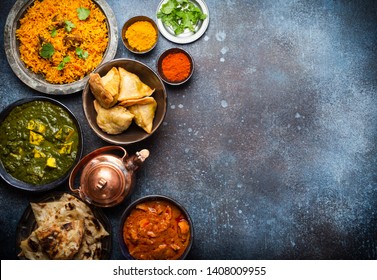 Overhead Of Indian Traditional Dishes And Appetizers: Chicken Curry, Pilaf, Naan Bread, Samosas, Paneer, Chutney On Rustic Background. Table With Choice Of Food Of Indian Cuisine, Space For Text