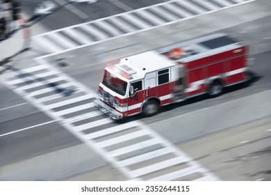 An overhead motion panned view of a fire engine racing to the scene of an emergency on a city street.