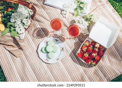 Overhead On Summer Picnic. Strawberries, Macaroons, Beverage And Basket With Flowers White Lilac. Top View, Flat Lay