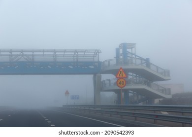 Overhead Passage  Through The Highway In The Mist. Empty Road With Road Signs.