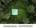 Overhead perspective of a observation tower cabin nestled in lush woodland during daylight hours.