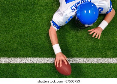 Overhead photo of an American football player making a one handed touchdown. The uniform he's wearing is one I had made using my name and does not represent any actual team colours.