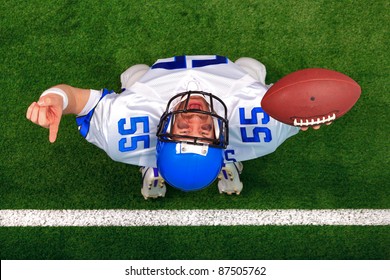 Overhead Photo Of An American Football Player Making A Touchdown Celebration Looking Up In The Air With His Finger Raised. The Uniform He's Wearing Does Not Represent Any Actual Team Colours.