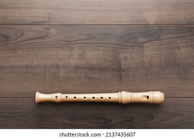 Overhead photo of block flute with copy space. Flat lay top-down composition of wooden recorder on the wooden background.