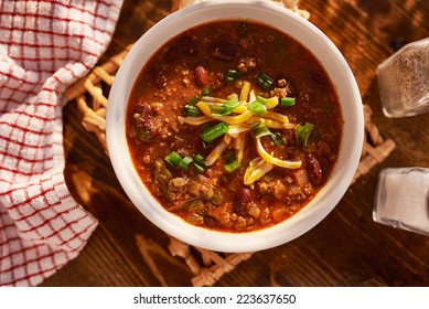 Overhead Photo Of A Bowl Of Chili With Cheese And Green Onions