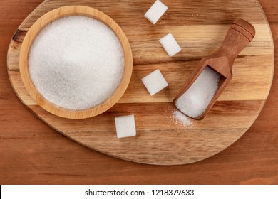 An Overhead Photo Of A Bowl And A Scoop Of White Sugar, With Sugar Cubes, Shot From The Top On Dark Rustic Wooden Backgrounds With Copy Space