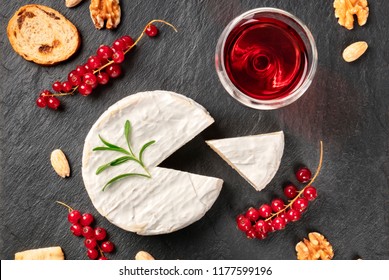 An Overhead Photo Of Camembert Cheese With A Glass Of Red Wine, Fruits And Nuts, Shot From Above On A Black Background