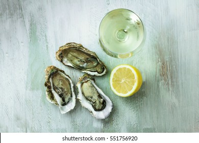 An Overhead Photo Of Freshly Opened Oysters With A Slice Of Lemon And A Glass Of White Wine, On A Wooden Background Texture With Copyspace