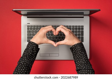 Overhead photo of grey laptop and hands with gesture as heart isolated on the red backdrop - Powered by Shutterstock