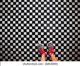 An Overhead Photo Of A Pair Of Tennis Shoes On A Grungy Dirty Checkered Tile Floor