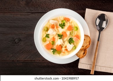 An Overhead Photo Of A Plate Of Chicken, Vegetables, And Noodles Soup, Shot From Above On A Dark Rustic Texture With Slices Of Bread And A Spoon, And A Place For Text