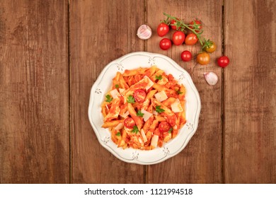 An Overhead Photo Of A Plate Of Pasta With Tomato Sauce, Chicken, And Cheese. Penne Rigate With Cherry Tomatoes And Fresh Parsley Leaves, On A Dark Rustic Texture With Ingredients And Copy Space