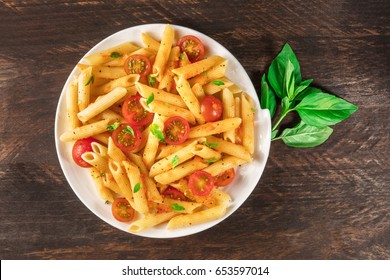 An Overhead Photo Of A Plate Of Pasta With Tomato Sauce. Penne Rigate With Cherry Tomatoes And Fresh Basil Leaves, On A Dark Rustic Texture With A Place For Text