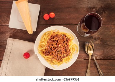 An Overhead Photo Of A Plate Of Spaghetti Bolognese, With Meat And Tomato Sauce, With A Glass Of Red Wine, A Slice Of Parmesan Cheese, Cherry Tomatoes, And A Place For Text