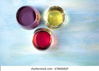 An Overhead Photo Of Three Glasses Of Wine, Red, White, And Rose, On A Teal Blue Background With A Place For Text