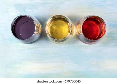 An Overhead Photo Of Three Glasses Of Wine, Red, White, And Rose, On A Teal Blue Background With A Place For Text