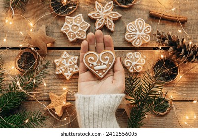 Overhead photo of woman holding gingerbread christmas cookie over wooden boards with decorations - Powered by Shutterstock