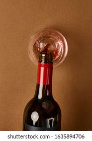 Overhead Photography Of A Bottle Of Red Wine Pouring Into A Stemless Wine Glass Against A Warm Caramel Coloured Background