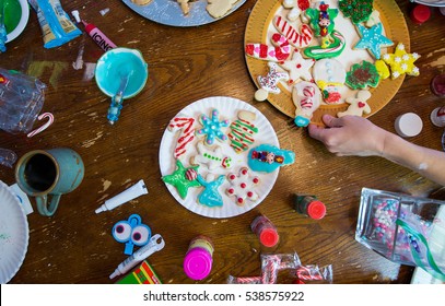 Overhead Of Platters Of Decorated Christmas Cookies And A Cup Of Coffee With A Hand