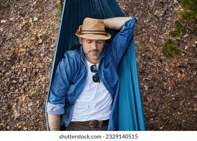 Overhead portrait of handsome adult man sleeping in hammock in forest taking nap during hiking trip - Powered by Shutterstock