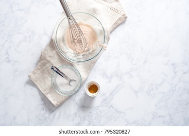 Overhead Of Powdered Sugar Glaze Or Icing In Glass Bowl With Additional Cream, Cinnamon, And Tablespoon Elements.