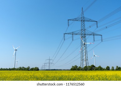 Overhead power lines in a field of blooming oilseed rape seen in rural Germany