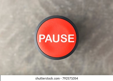 Overhead of a red pause push button over a blurred gray background - Shutterstock ID 792571054