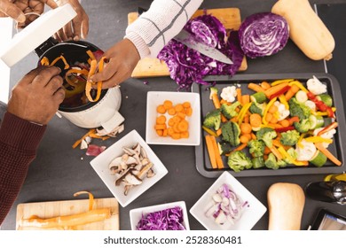 Overhead of senior biracial couple wearing aprons composting food waste in kitchen at home. Senior lifestyle, retirement, ecology, food, cooking and domestic life, unaltered. - Powered by Shutterstock