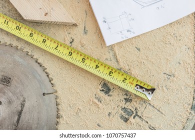 Overhead Of Shop Table; Sawdust, Tape Measure, Wood Block, Saw Blade, Blueprints