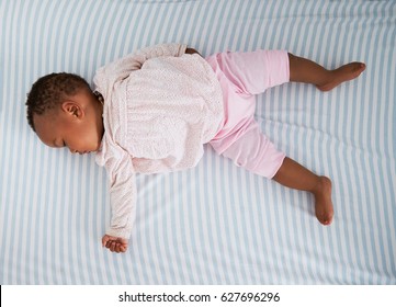 Overhead Shot Of Baby Girl Sleeping In Nursery Cot