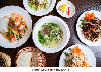 Overhead Shot Of Big Vietnamese Dinner Menu,business Lunch In Asia.Enjoy Popular Pho Bo Soup With Noodles & Boiled Beef Meat.Plates With Different Vegetable Salads & Rice.