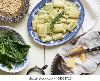 Overhead Shot Of A Blue China Platter Filled With Pesto Rigatoni. Fresh Herbs, Creamer, And Cheese Also On Table. 