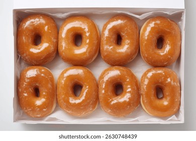 Una toma aérea de una caja llena de donas glaseadas, perfecto para el desayuno o un dulce. Se ven deliciosos.