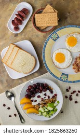 An Overhead Shot Of A Breakfast Spread Composed Of Eggs, Fruits, Bread, Biscuits And Sausage