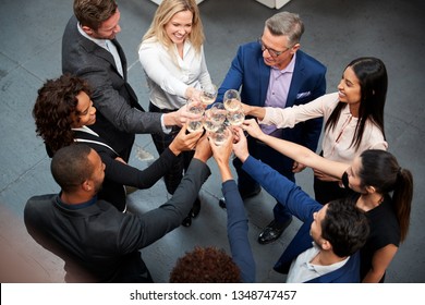 Overhead Shot Of Business Team Celebrating Success With Champagne Toast In Modern Office