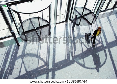 Overhead shot of a businesswoman walking through revolving door with a suitcase in her hand with copy space available.