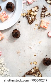 Overhead Shot Of Candy Cane Fudge, Dark Chocolate Oreo Truffles And Chocolate Almond Bark With Peppermints On White Surface With Christmas Ornament.