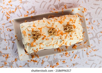 An Overhead Shot Of A Carrot Cake With Almonds And Nuts In A Plate On A White Table