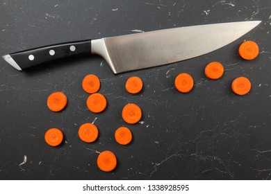 Overhead Shot, Carrot Slices To Small Circles, With Chef Knife Above, On Black Marble Working Board