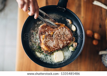 Overhead shot of chef preparing ribeye with butter, thyme and garlic. Keto diet.