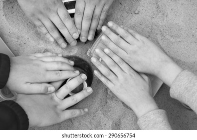 Overhead Shot Of The Children Hands Playing In A Sandbox In Black And White