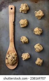 Overhead Shot Of Chocolate Chip Cookie Dough On A Cookie Sheet, With A Wooden Spoon Holding A Big Gob Of The Raw Dough. Vertical Format.