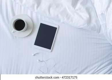 Kopfaufnahmen von Kaffee, Tablet und Kopfhörer im Bettkonzept