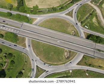 Overhead shot of a complex road junction surrounded by lush greenery and fields