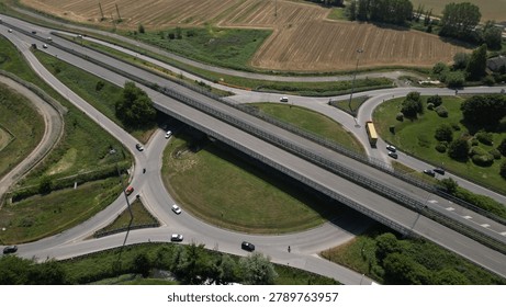Overhead shot of a complex road junction surrounded by lush countryside and infrastructure